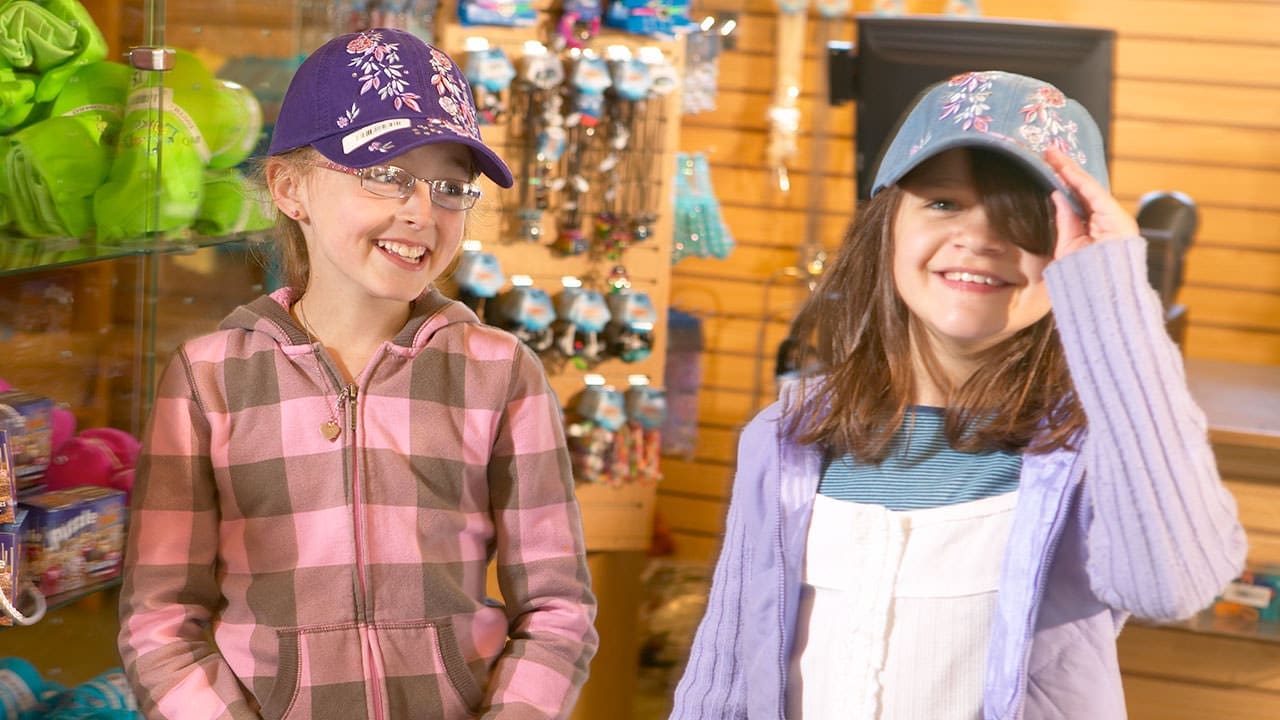 Filles avec des chapeaux dans une boutique de cadeaux